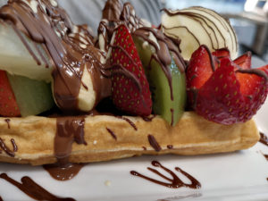 Fresh cut fruits and chocolate over Belgium waffle